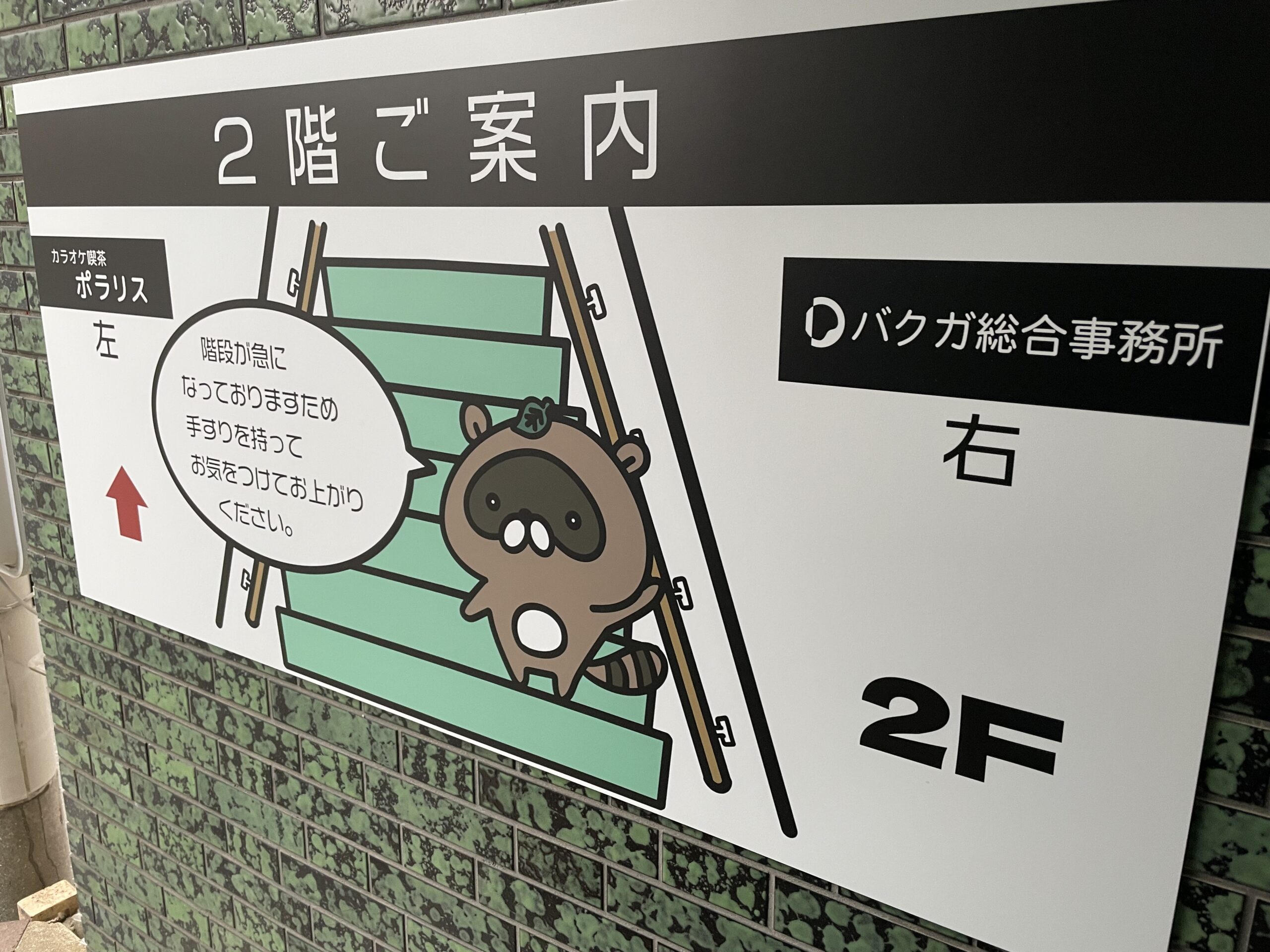 階段前に設置されたバクガ総合事務所の案内
